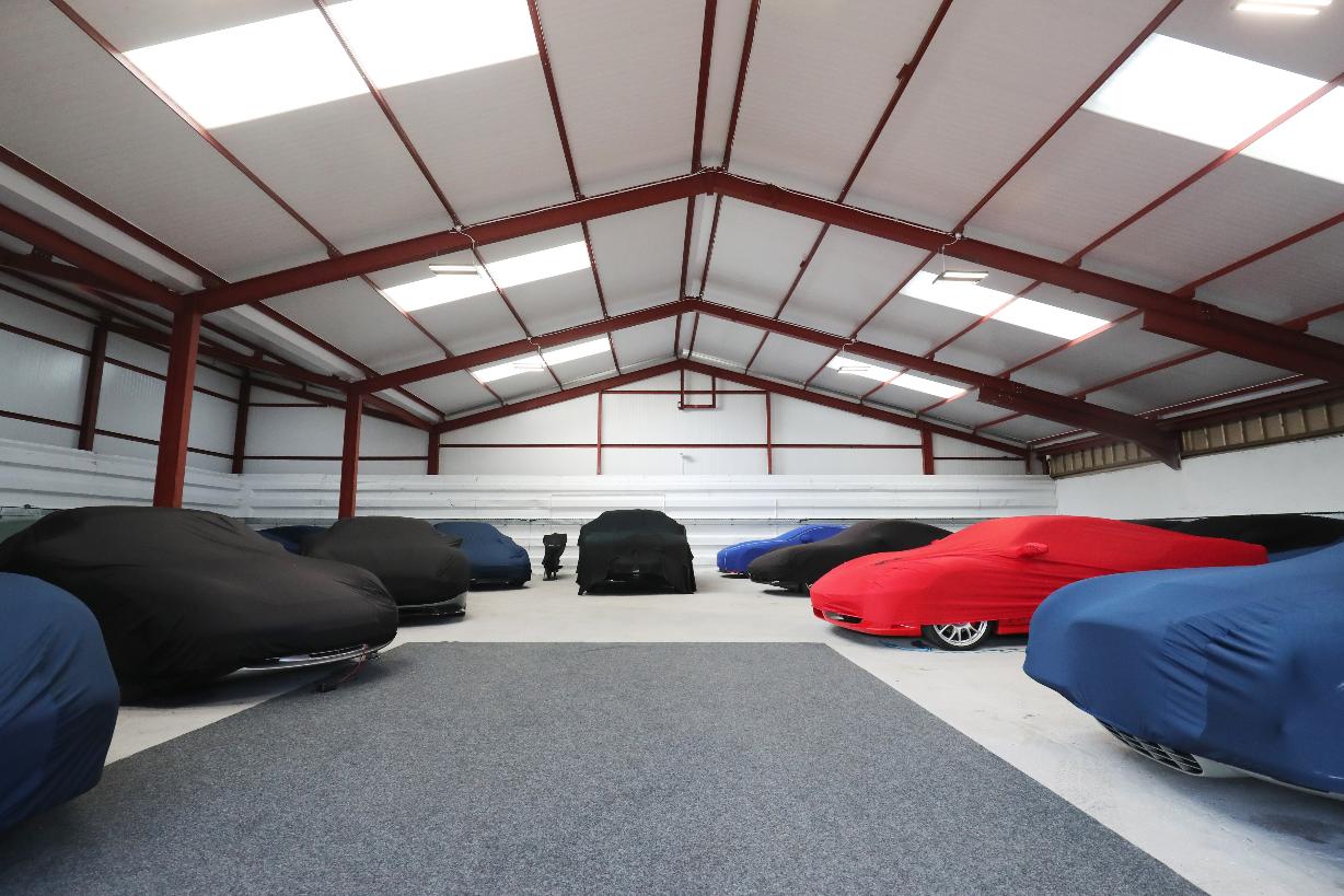 An example of a clean and carpeted, well presented storage unit full of luxury sports cars.